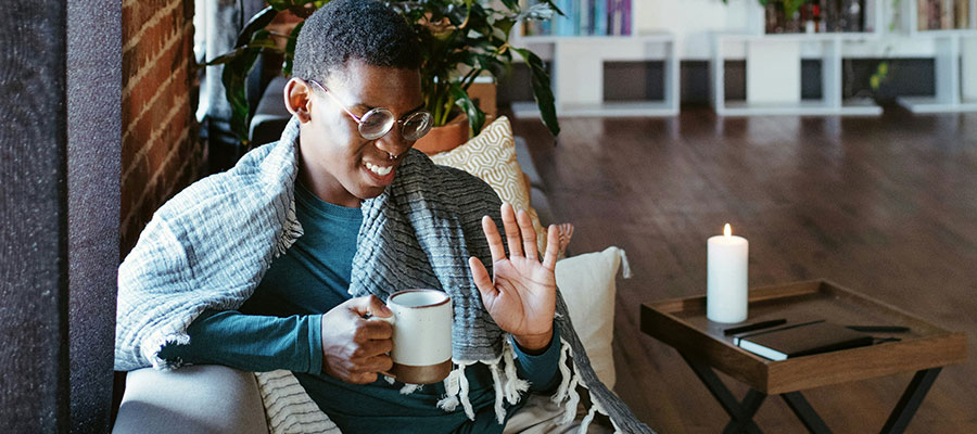 ragazzo felice seduto sul divano beve una tazza di caffè